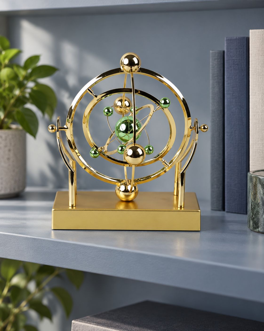 Gold celestial orbit pendulum with green and gold spheres on a shelf beside books