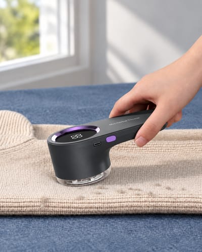 Grey fabric shaver held against a beige knitted garment.