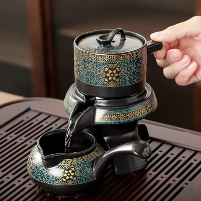 Teal floral tea vessel pouring into its matching pitcher.
