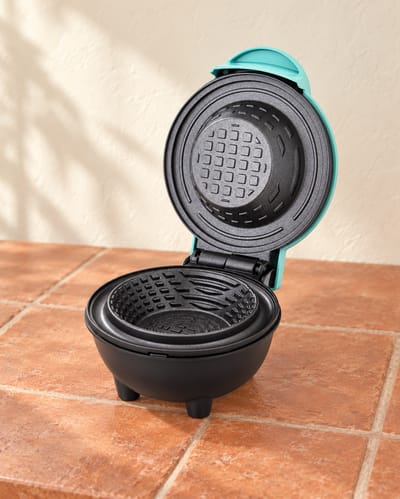 Open waffle bowl maker showing its round patterned cooking plates.