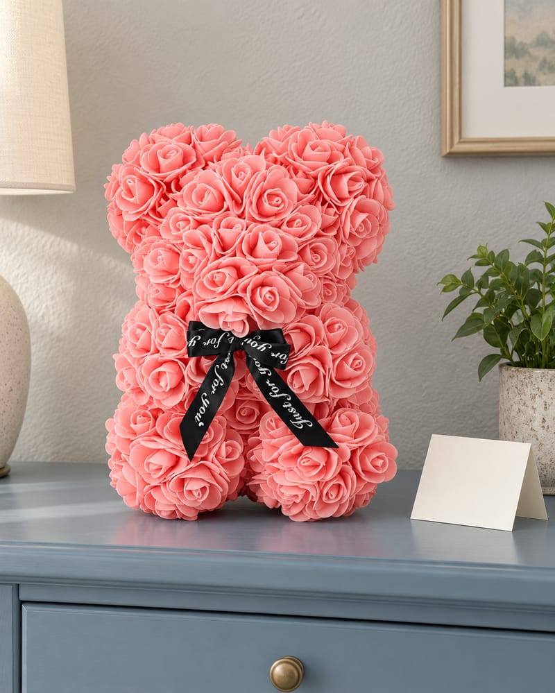 Teddy bear covered in roses, sitting on a dresser beside a blank card
